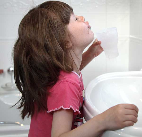 Ein Mädchen gurgelt mit Schungit-Wasser